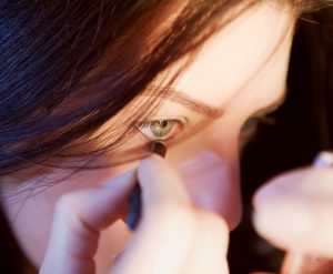 Close-up d'une femme appliquant précisément de l'eyeliner avec concentration.
