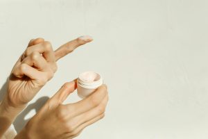 A close-up image showing hands applying facial cream, reflecting a minimalist skincare routine. Gros plan montrant des mains appliquant une crème faciale, reflétant une routine de soins minimaliste.