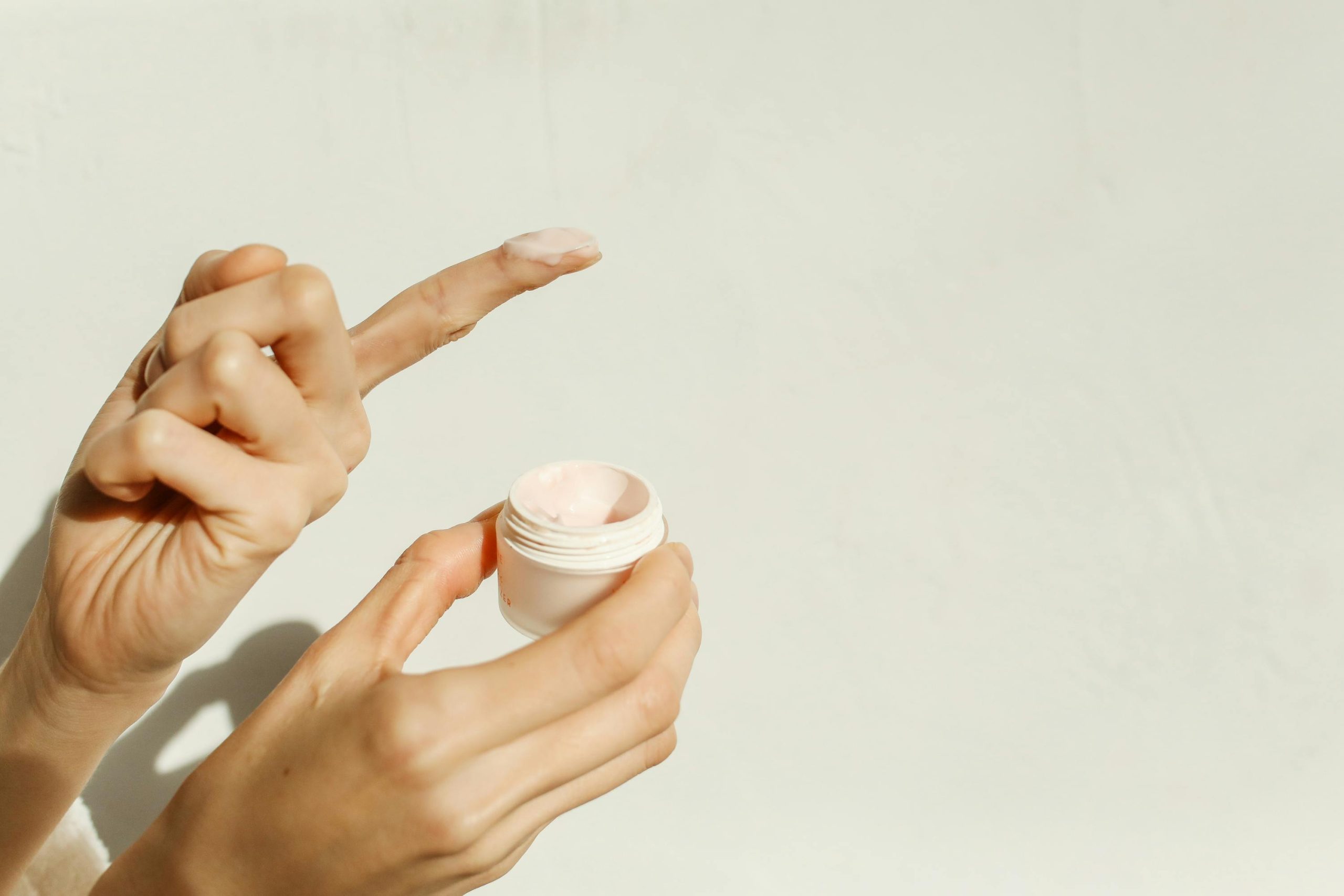 A close-up image showing hands applying facial cream, reflecting a minimalist skincare routine. Gros plan montrant des mains appliquant une crème faciale, reflétant une routine de soins minimaliste.