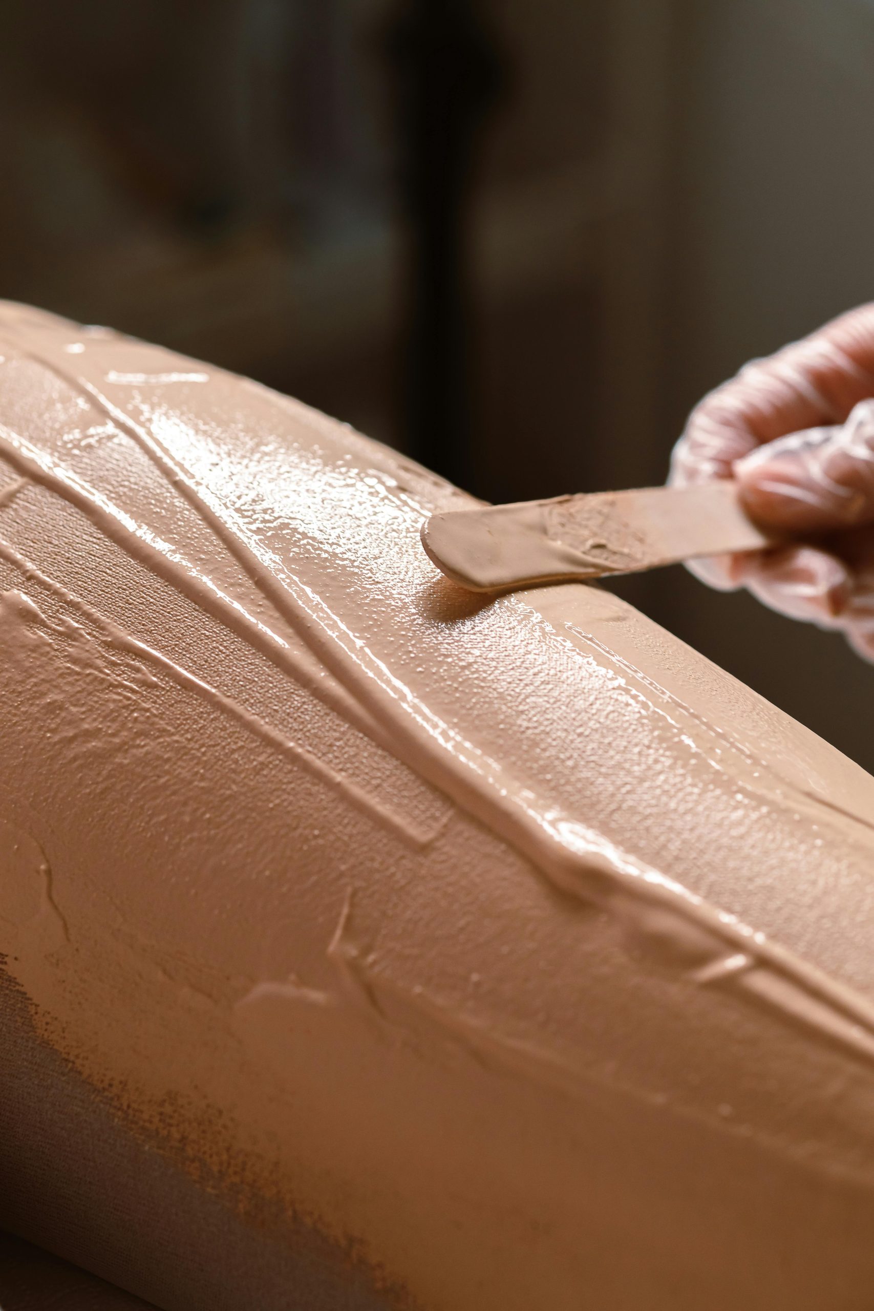 Gros plan détaillé d'une main appliquant une crème de soin de la peau avec un bâton en bois sur la peau.