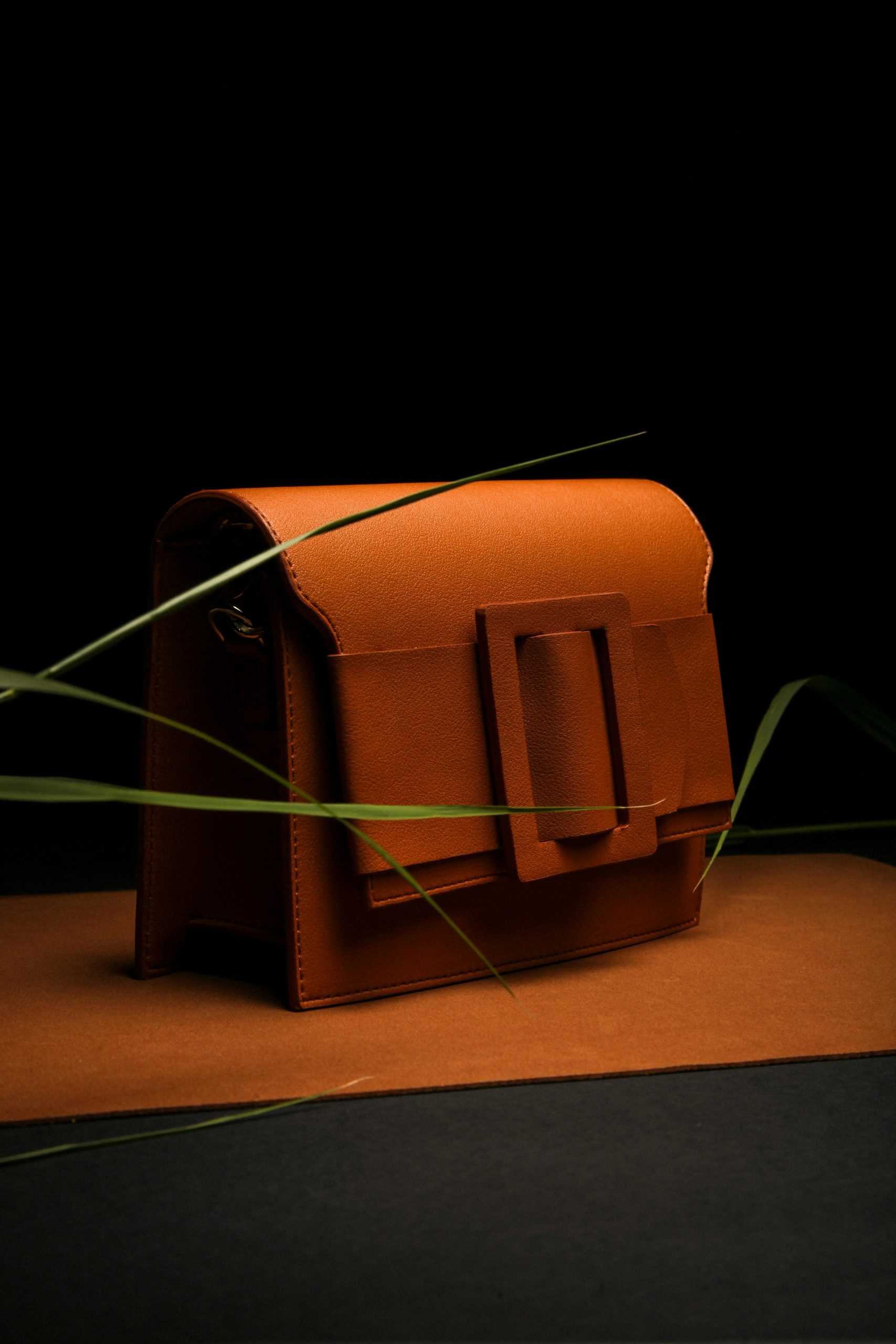 Stylish brown leather bag showcased elegantly in a studio setting with dramatic lighting. Un sac à main en cuir marron élégant présenté avec style dans un décor de studio avec un éclairage dramatique.