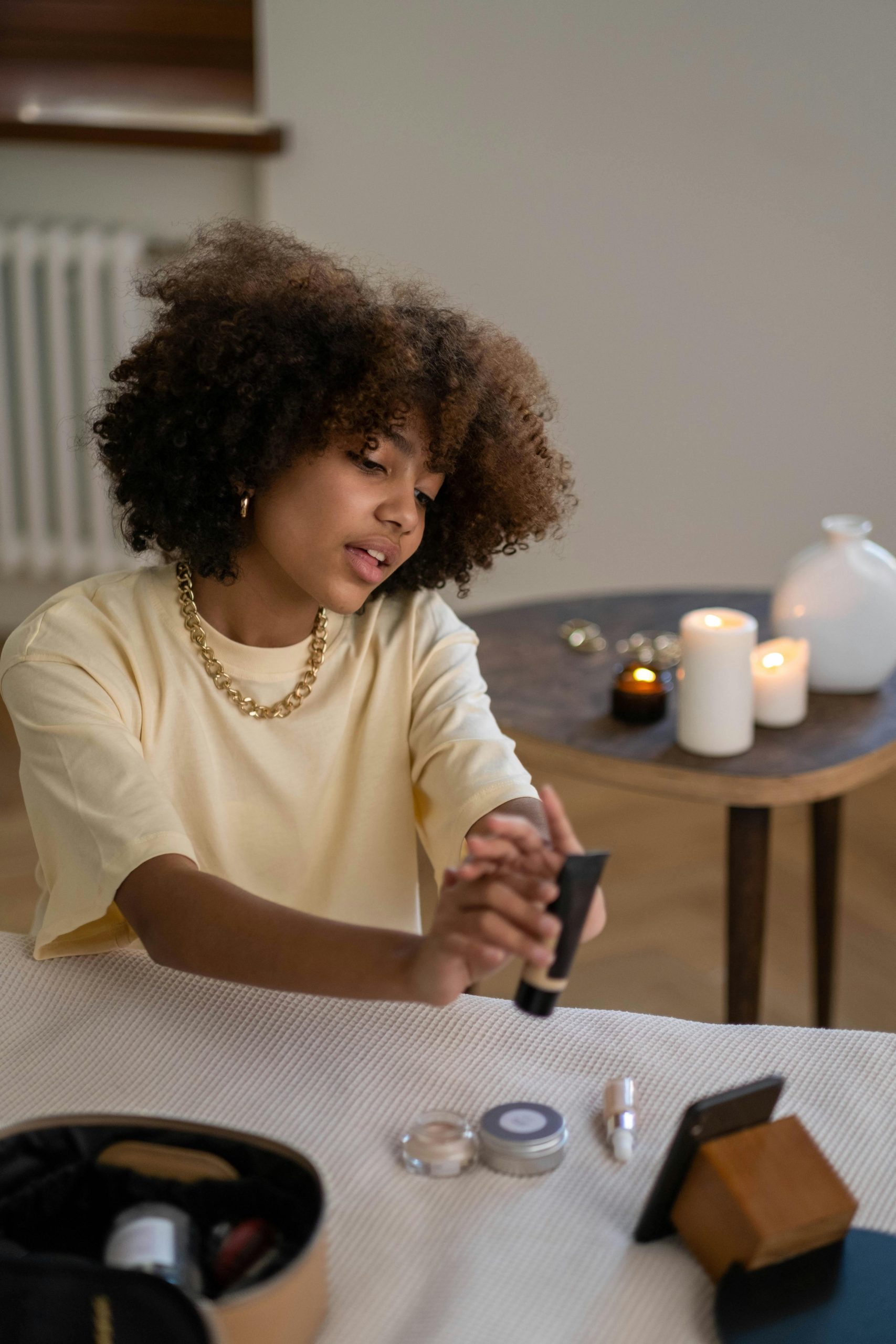 A young beauty influencer reviews skincare products in a cozy indoor setting with candles. Une jeune influenceuse beauté teste des produits de soin de la peau dans un cadre intérieur confortable avec des bougies.