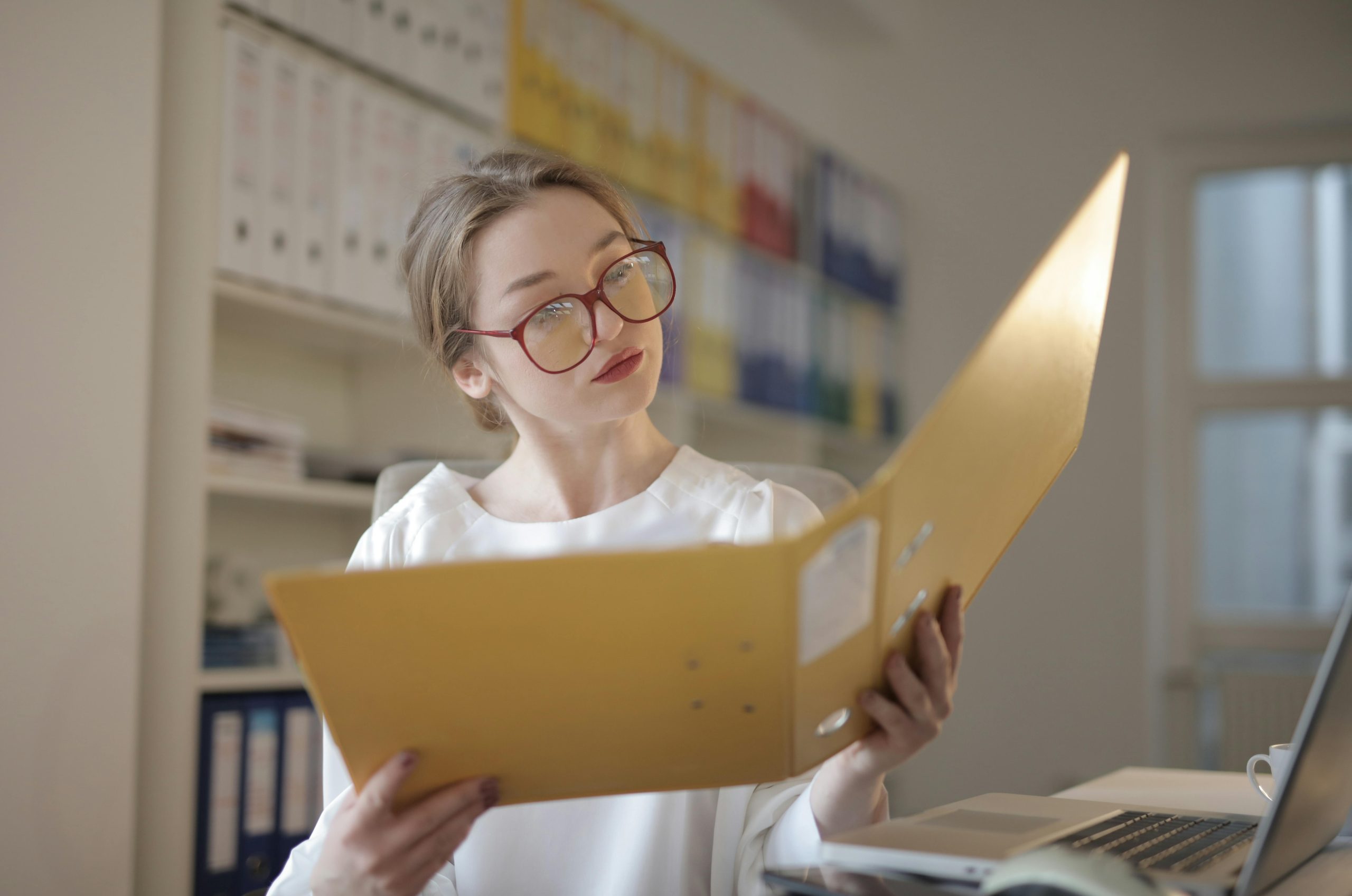 Caucasian woman intensely reading documents in an office setting. Femme caucasienne lisant intensément des documents dans un bureau.