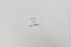 Carte de célébration colorée avec des confettis sur fond blanc. Parfait pour les occasions festives.