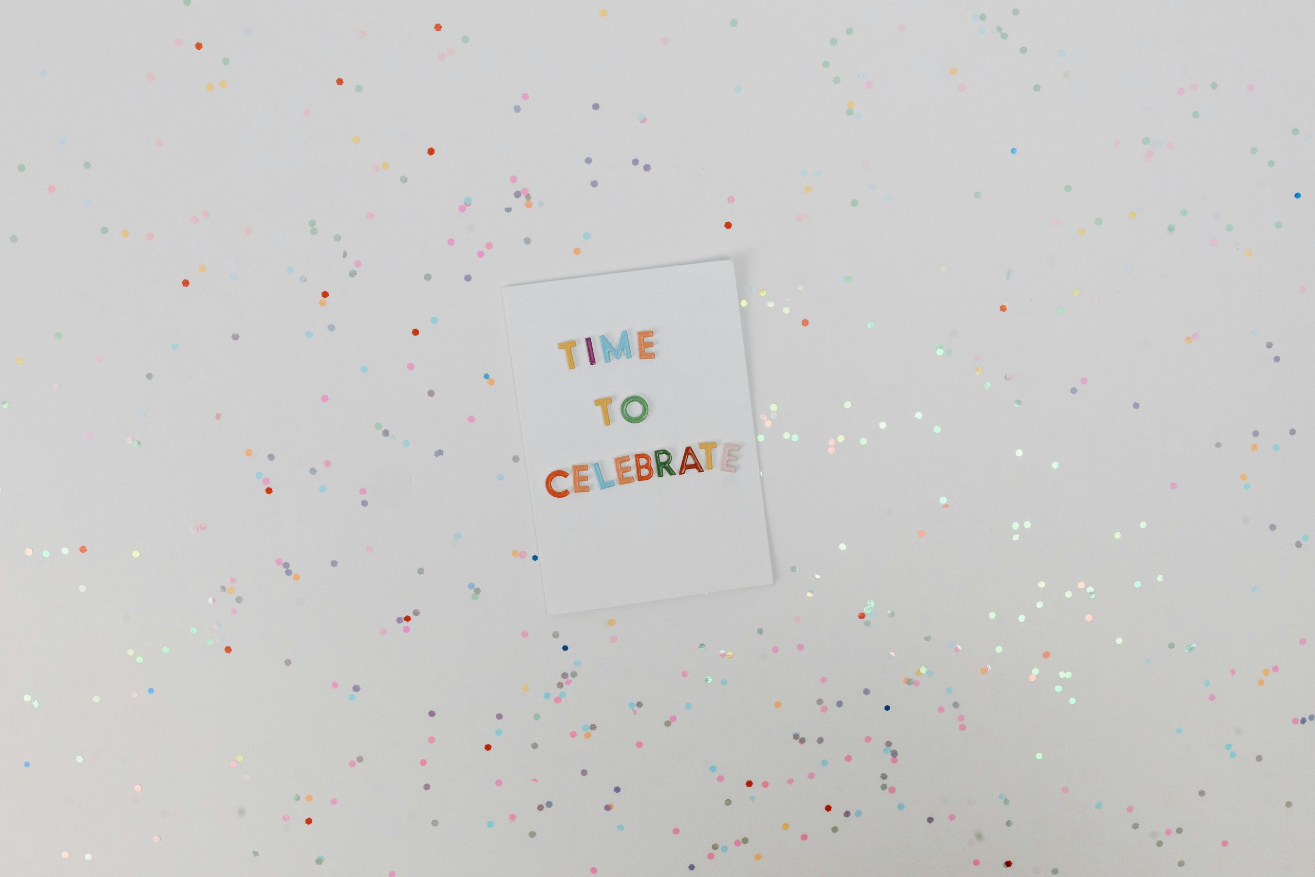 Carte de célébration colorée avec des confettis sur fond blanc. Parfait pour les occasions festives.