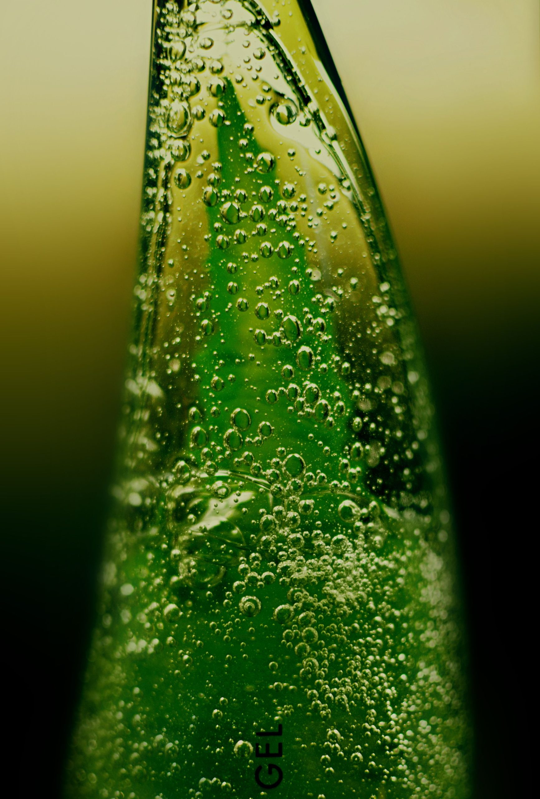 Gros plan d'une bouteille de gel d'aloe vera vert avec des bulles visibles, mettant l'accent sur la fraîcheur.