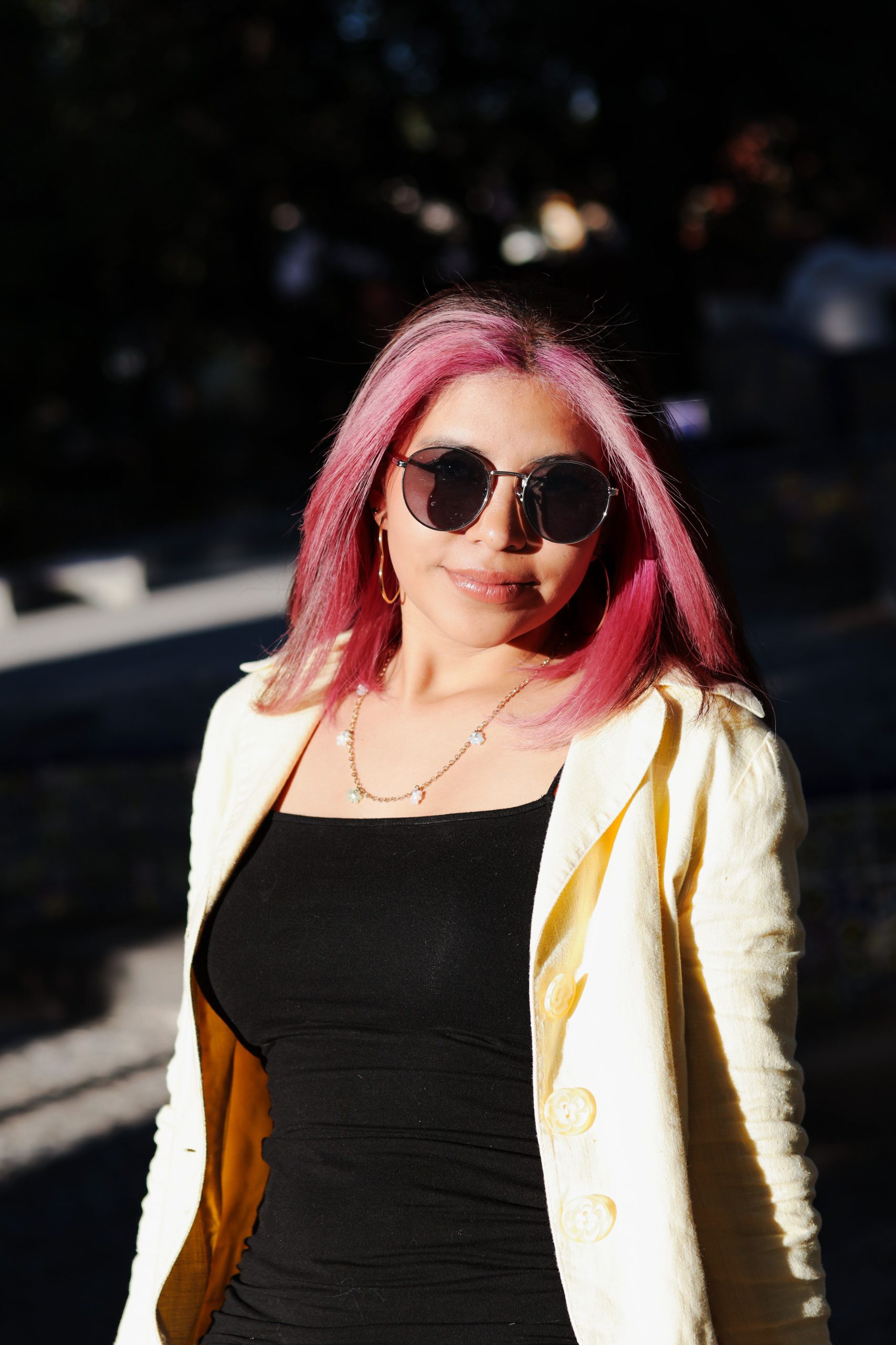 Femme à la mode avec cheveux roses et lunettes de soleil à la lumière vive du soleil.