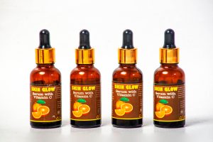 Four Vitamin C serum bottles arranged on a white background for skincare. Quatre flacons de sérum à la vitamine C arrangés sur un fond blanc pour les soins de la peau.