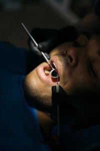 Detailed close-up of a dental examination with a mouth mirror and probe at a clinic. Gros plan détaillé d'un examen dentaire avec un miroir buccal et une sonde dans une clinique.
