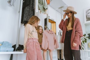 A mother and her daughters choose outfits in a stylish, cozy home setting. Une mère et ses filles choisissent des tenues dans un cadre élégant et confortable à la maison.