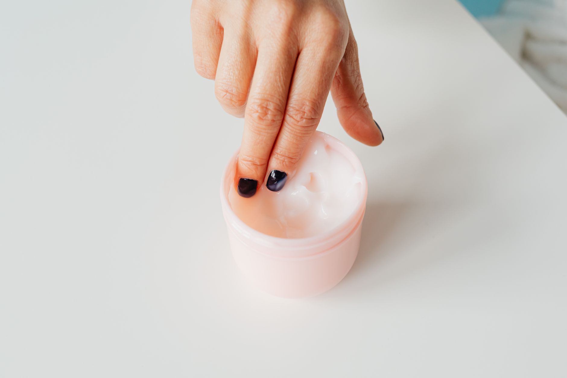 Main aux ongles manucurés appliquant une crème de soin