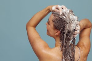 Femme qui applique du shampoing en mousse sur cheveux longs