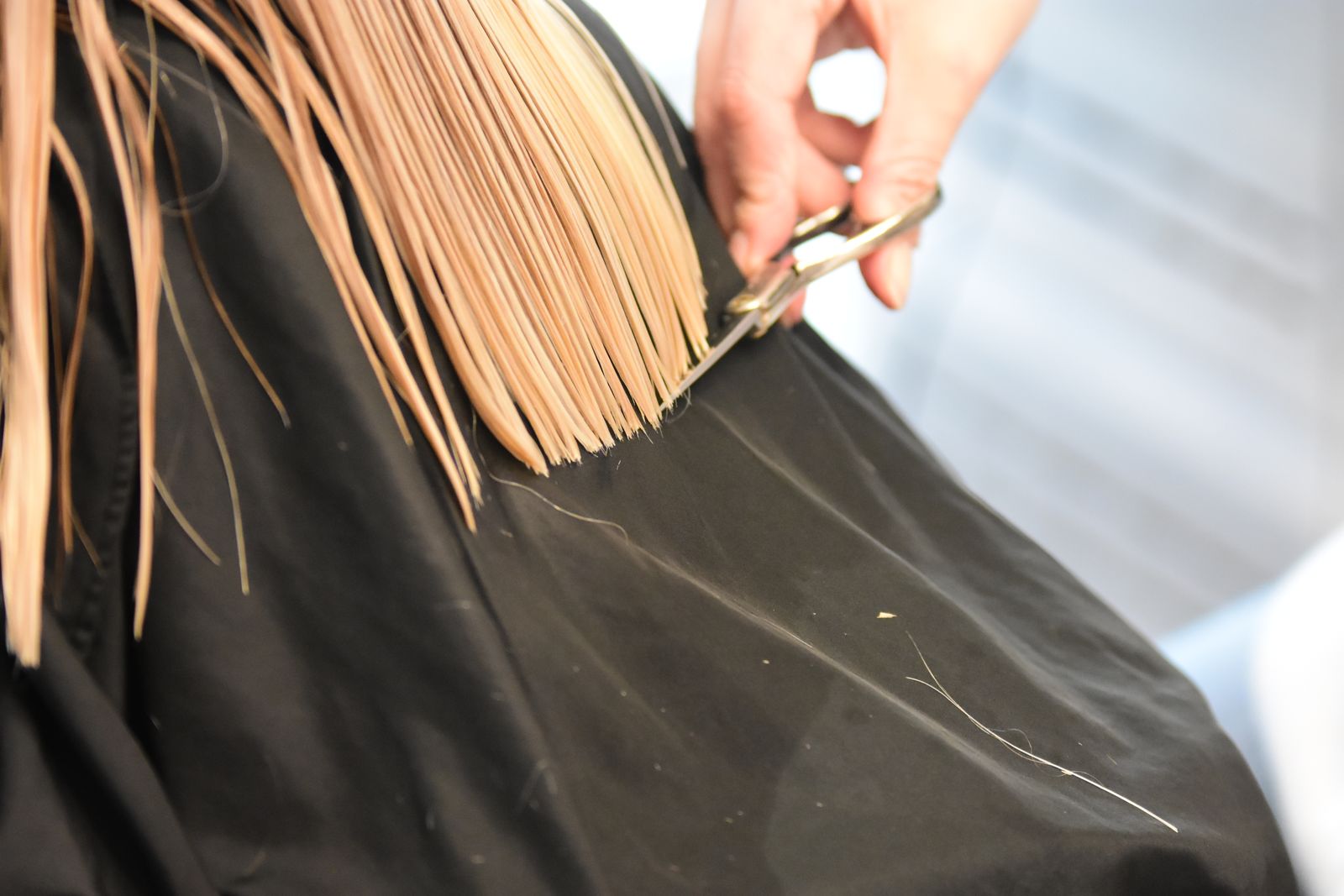 Coiffeuse coupant des cheveux blonds aux ciseaux en salon