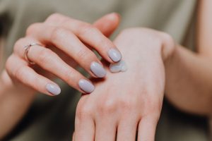 Femme appliquant une crème hydratante sur le dos de la main