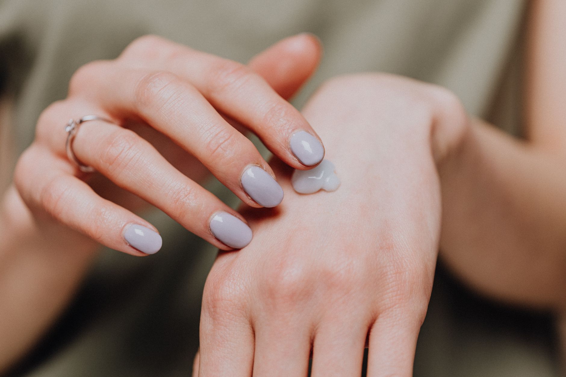 Femme appliquant une crème hydratante sur le dos de la main
