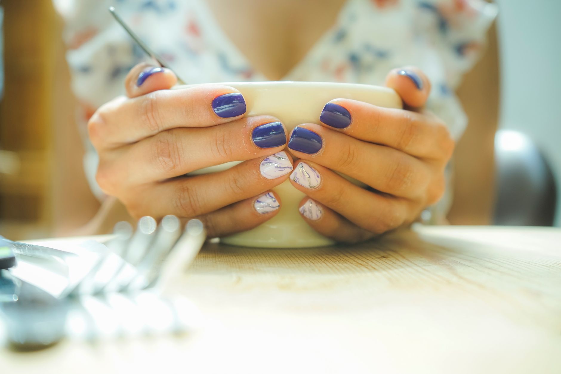 Mains aux ongles colores tenant une tasse