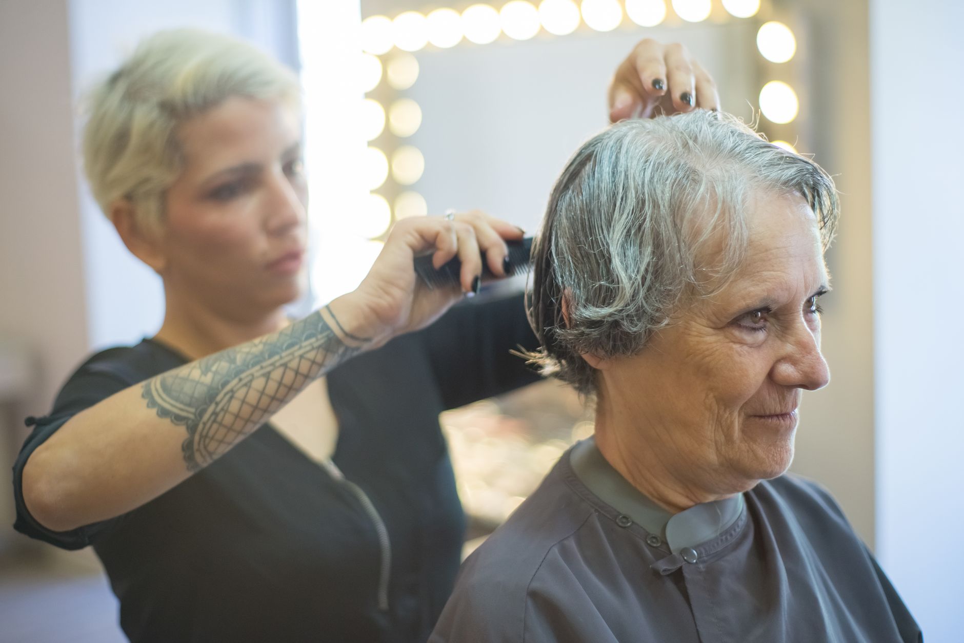 Coiffeuse coupant les cheveux d'une cliente en salon
