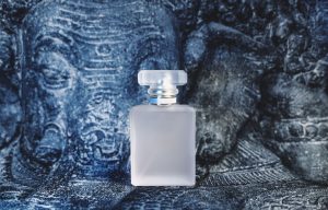 Flacon de parfum givré posé devant une sculpture texturée