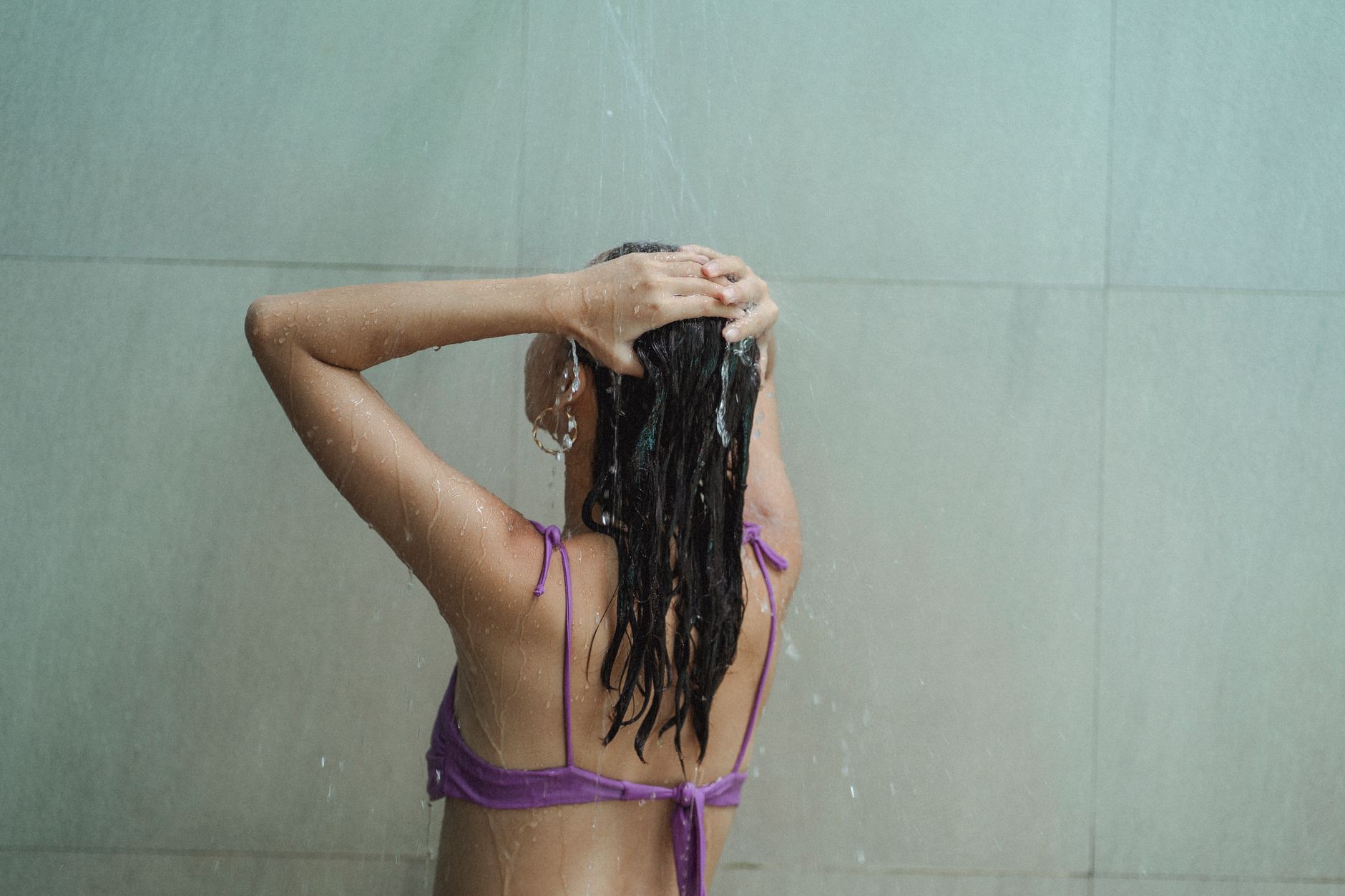 Femme se rinçant les cheveux sous la douche